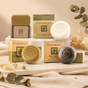 A collage of Tanamera brand body soaps and their boxes on a light gray background, showing multiple bars in different colors: brown, white, green, and black, each with its branded packaging.